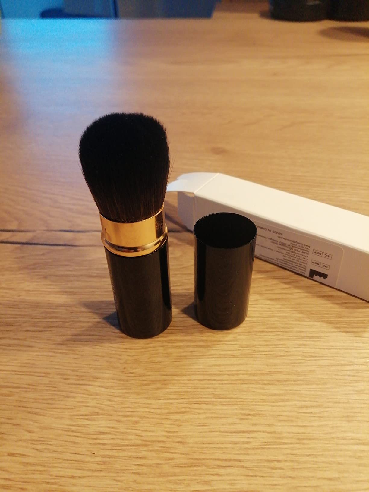 Gros pinceau kabuki rétractable posé sur un parquet